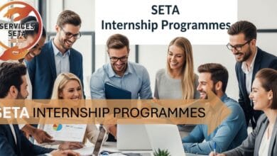 group of young adults (men and women of different ethnic backgrounds) in a modern office setting, smiling and collaborating around laptops and paperwork. A banner or text in the background says "SETA Internship Programmes".